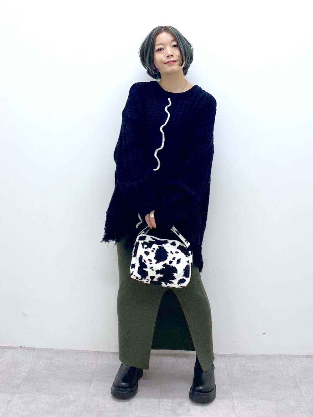 ブラック系のトップス、グリーン系のスカート、ブラック系のバッグを着用したレディースの冬コーディネートの2枚目の写真