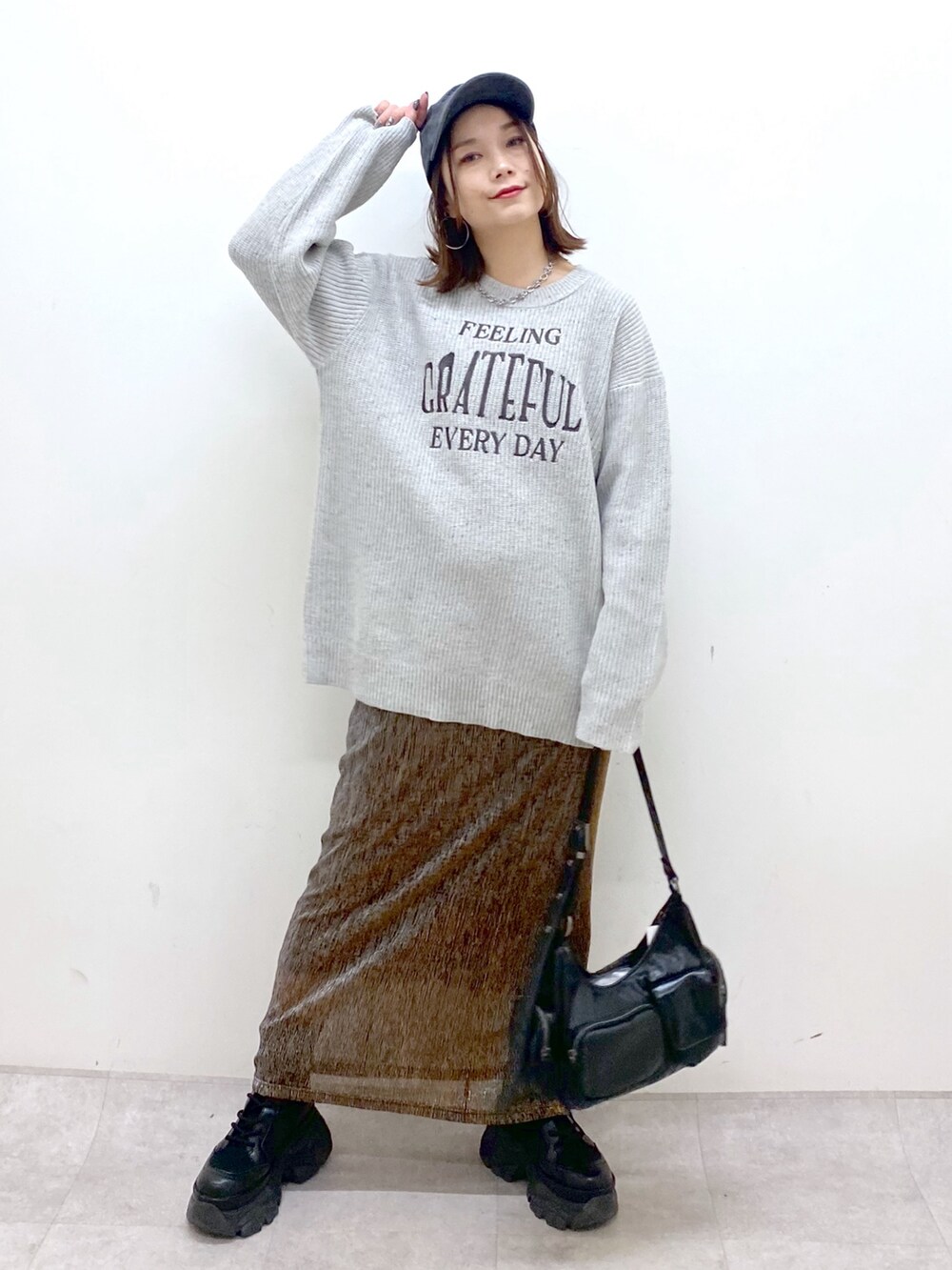 グレー系のニット/セーター、ゴールド系のスカート、ブラック系のショルダーバッグを着用したレディースの冬コーディネートの4枚目の写真