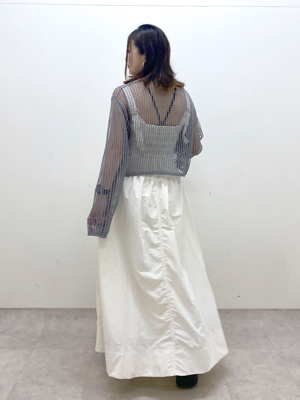 ホワイト系のワンピース、グレー系のカーディガン/ボレロ、ブラック系のサンダルを着用したレディースの春コーディネートの6枚目の写真