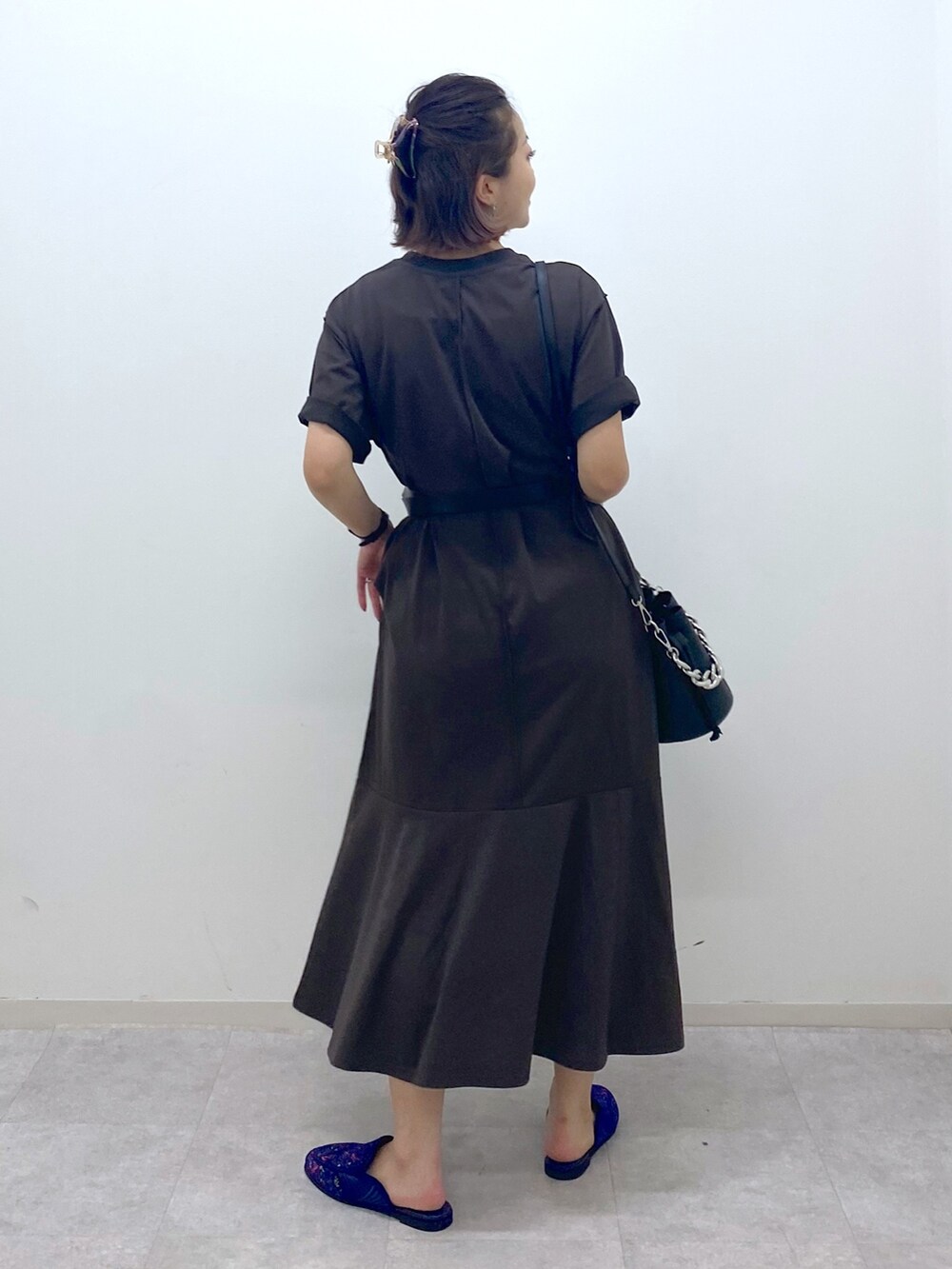 ブラック系のショルダーバッグ、ブラウン系のワンピース、ブルー系のスリッポンを着用したレディースの夏コーディネートの3枚目の写真