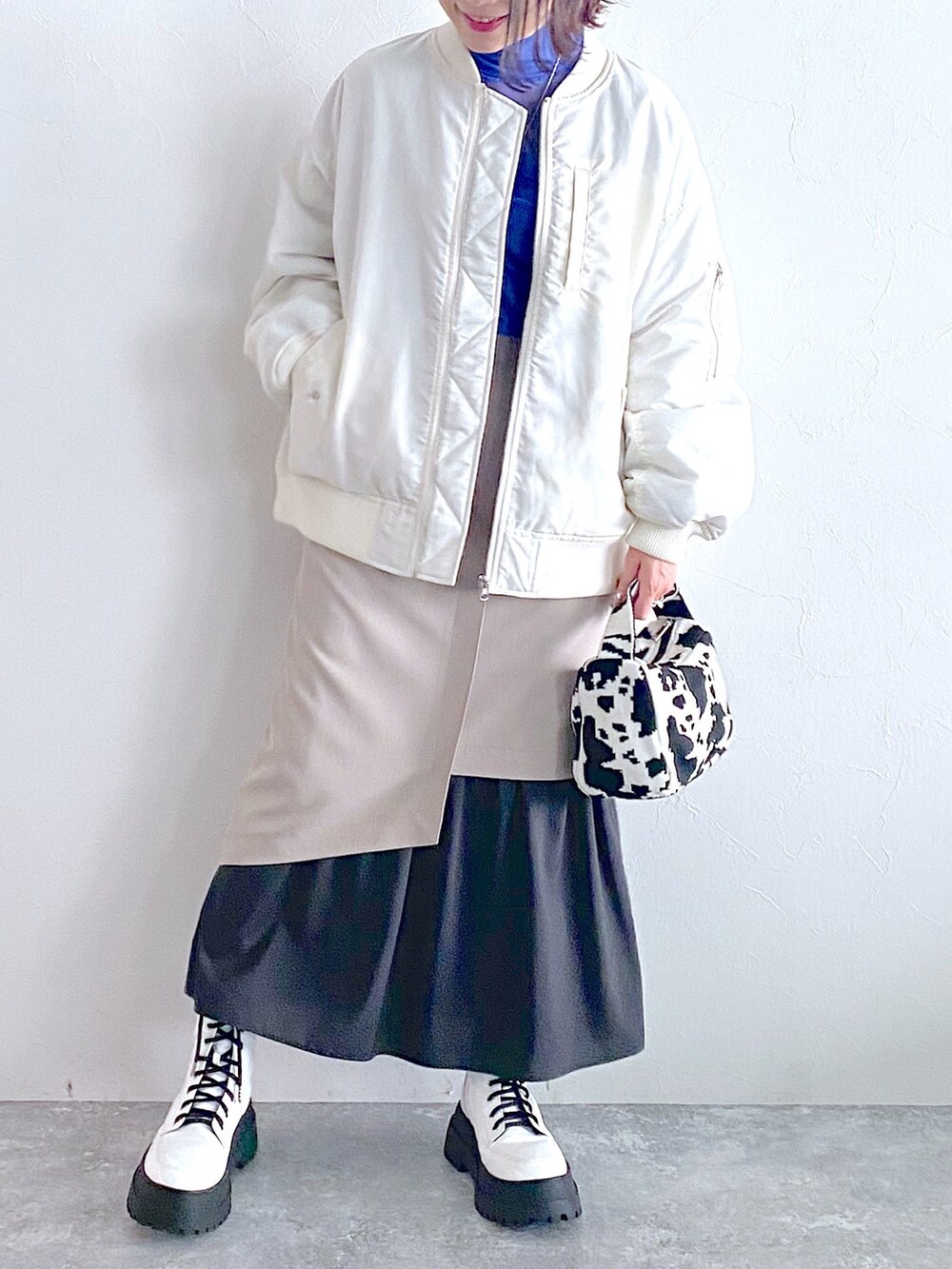 ホワイト系のMA-1、ベージュ系のスカート、ホワイト系のブーツを着用したレディースの夏コーディネートの5枚目の写真