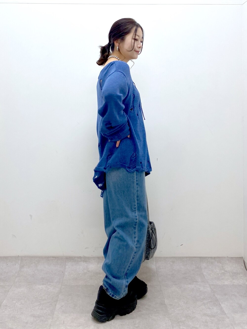 ブルー系のニット/セーター、ブルー系のデニムパンツ、ブラック系のトートバッグを着用したレディースの冬コーディネートの5枚目の写真