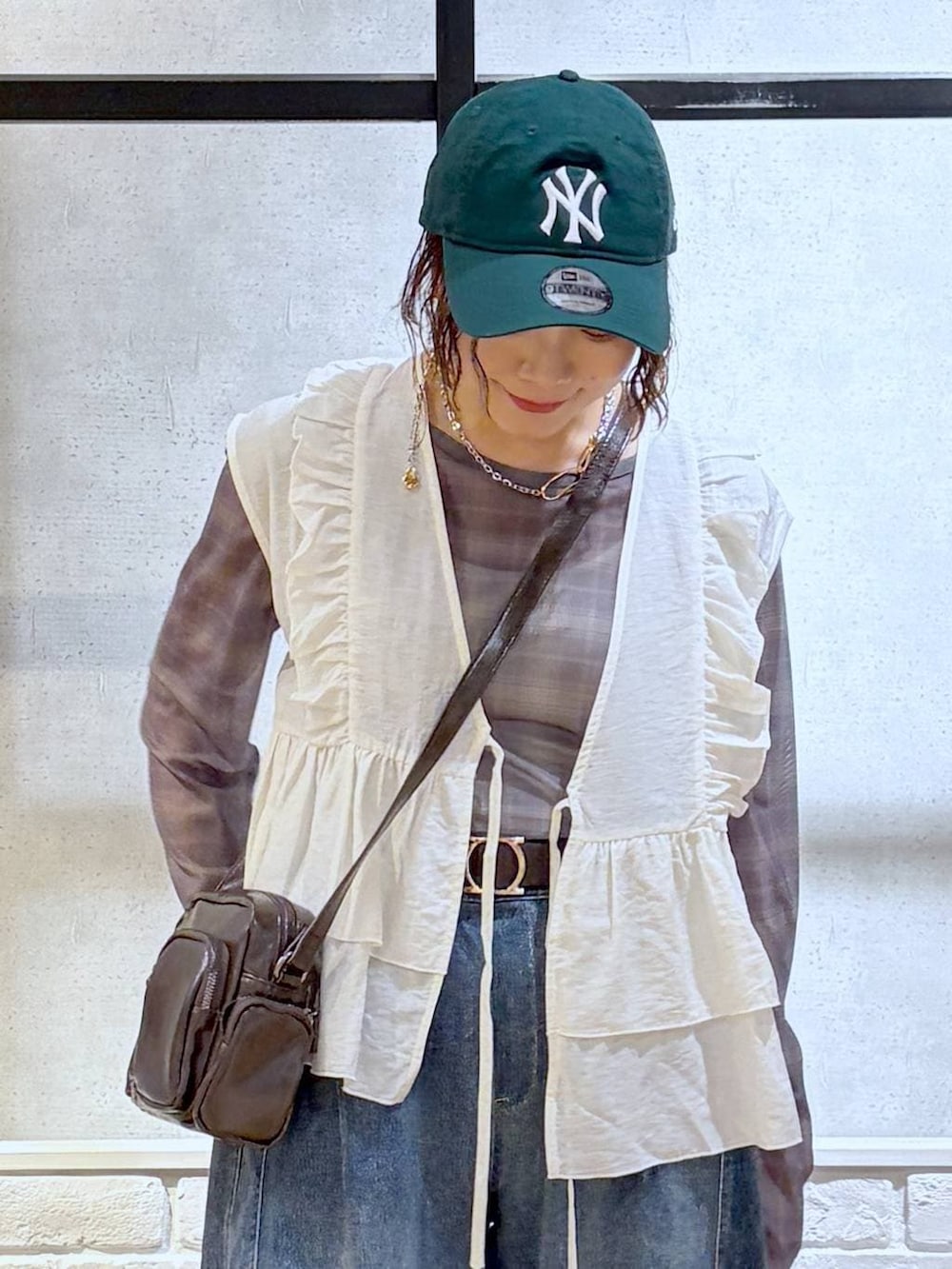 ホワイト系のスニーカー、ブラウン系のショルダーバッグ、ブルー系のデニムパンツを着用したレディースの春コーディネートの2枚目の写真