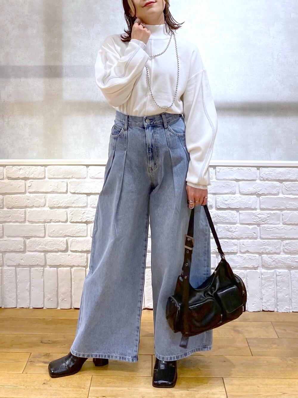 ホワイト系のニット/セーター、ブルー系のデニムパンツ、ブラック系のショルダーバッグを着用したレディースの冬コーディネートの3枚目の写真