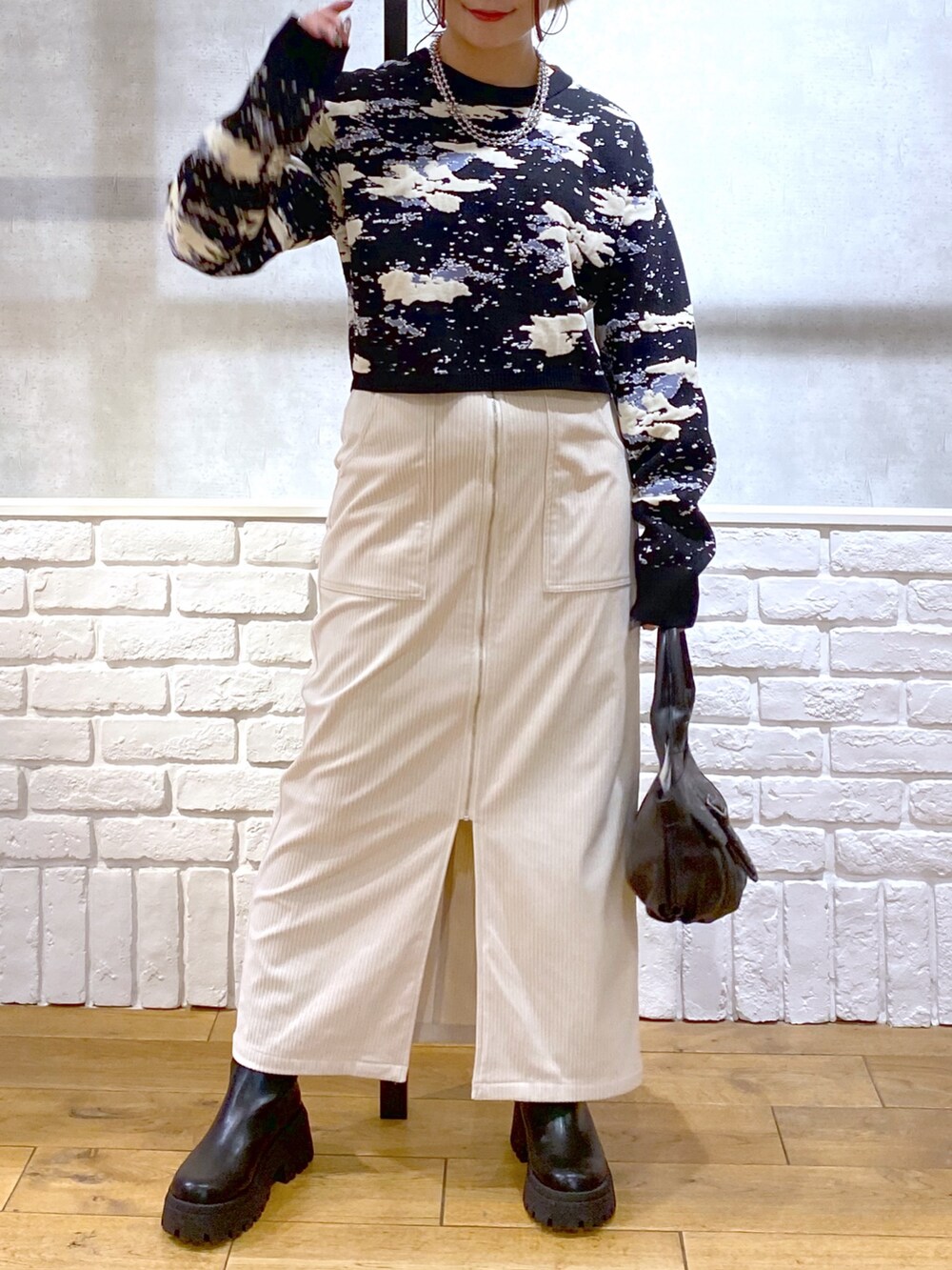 ブラック系のニット/セーター、ブラック系のハンドバッグ、ブラック系のブーツを着用したレディースの冬コーディネートの3枚目の写真