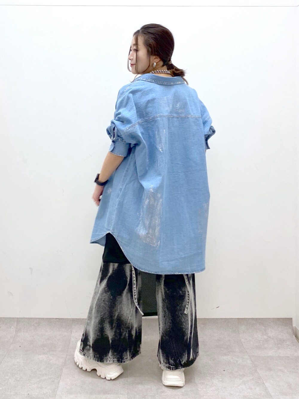 ブラック系のデニムパンツ、ホワイト系のスニーカー、ブラック系のワンピースを着用したレディースの春コーディネートの7枚目の写真