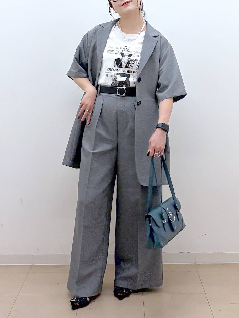 ホワイト系のTシャツ/カットソー、グレー系のスラックス、ブラック系のサンダルを着用したレディースの夏コーディネートの2枚目の写真