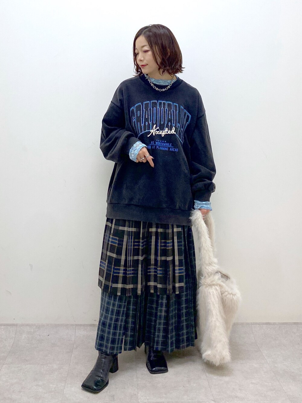 グレー系のスウェット、ブルー系のスカート、ホワイト系のショルダーバッグを着用したレディースの秋コーディネートの8枚目の写真