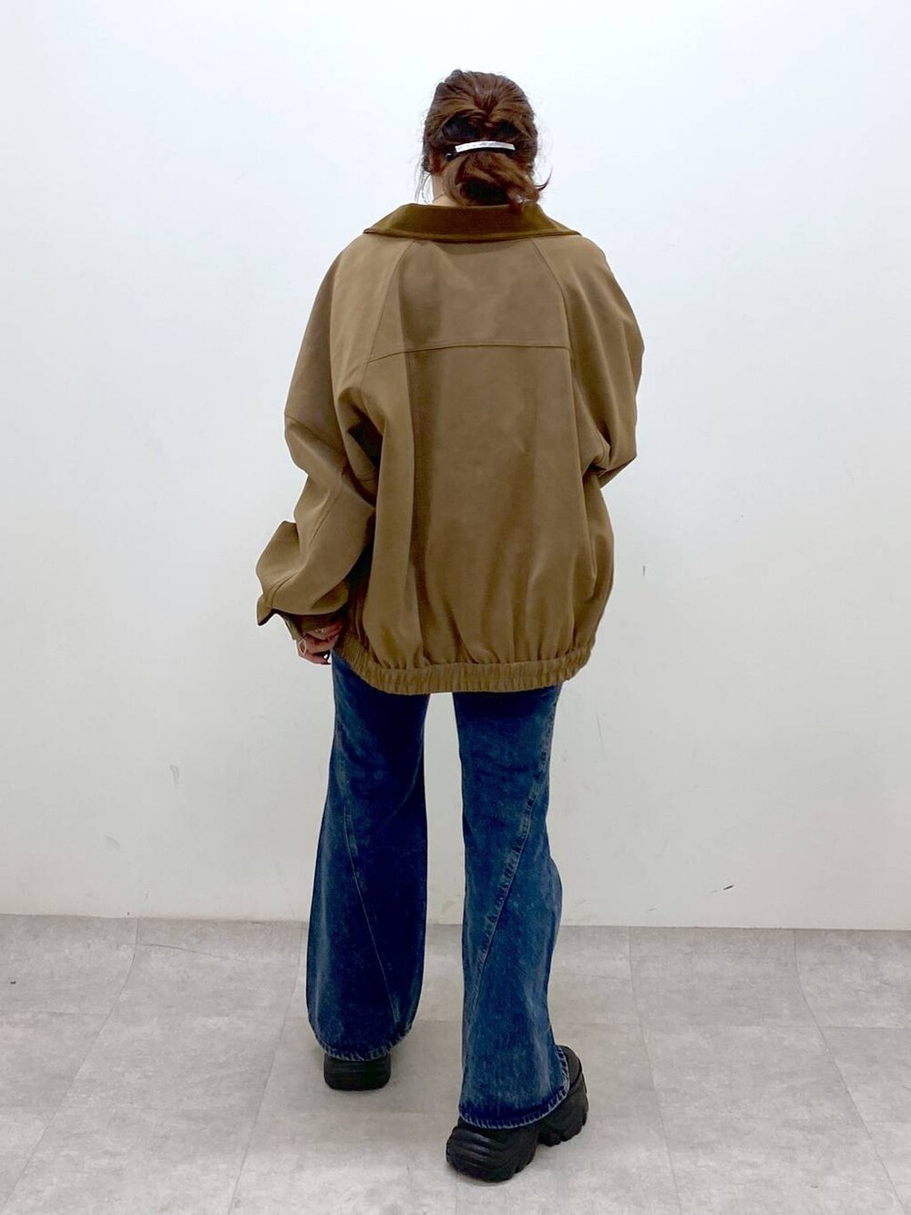 ブラック系のスニーカー、ブルー系のデニムパンツ、ブラウン系のショルダーバッグを着用したレディースの秋コーディネートの6枚目の写真