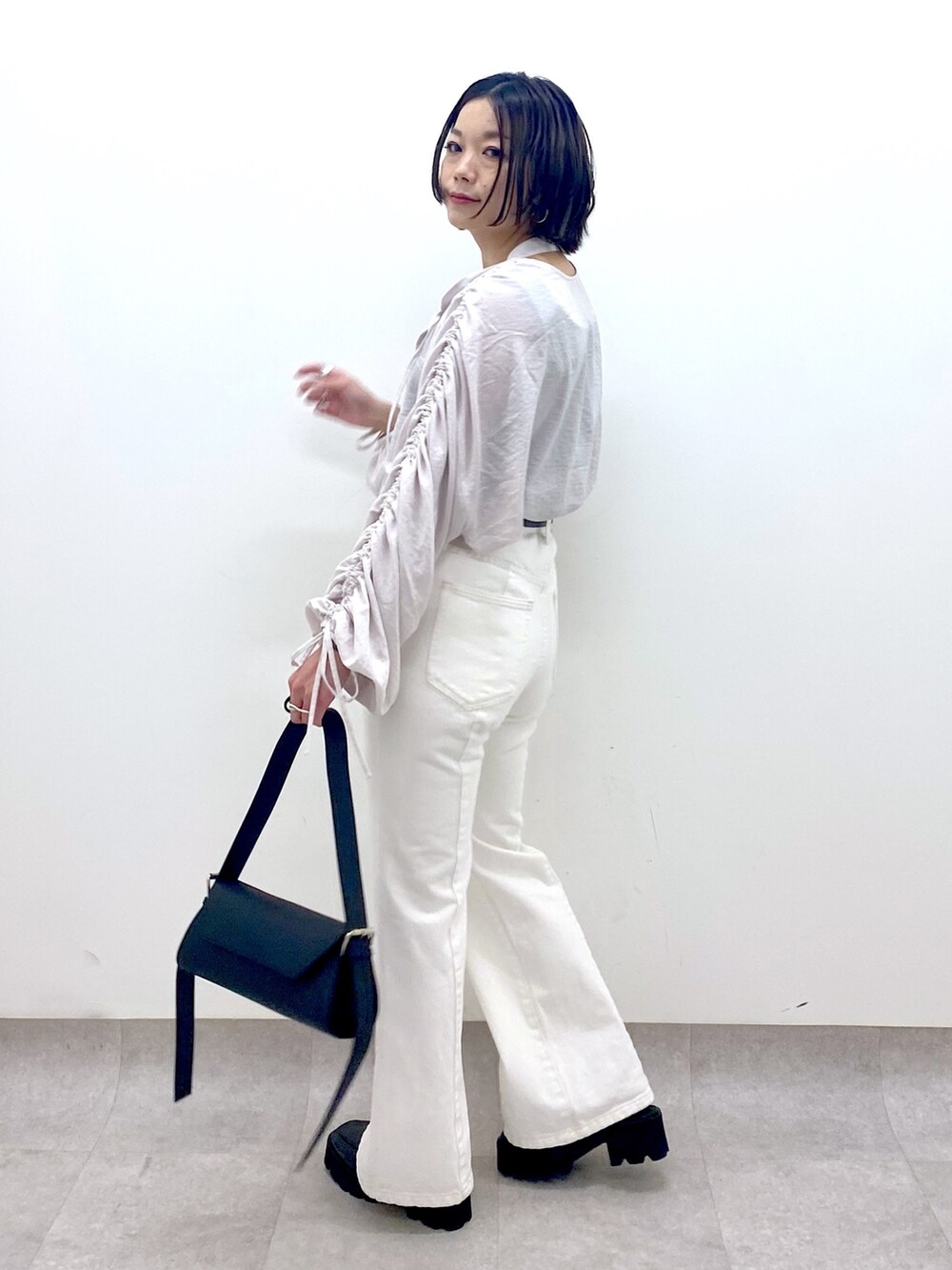 ホワイト系のパンツ、ブラック系のバッグ、ブラック系のローファーを着用したレディースの春コーディネートの2枚目の写真