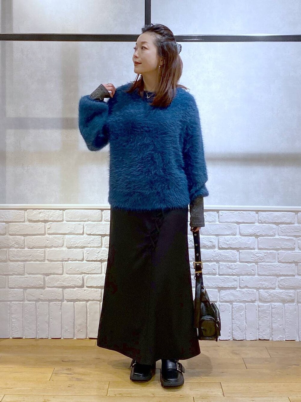 シルバー系のTシャツ/カットソー、ブラック系のブーツ、ブルー系のニット/セーターを着用したレディースの冬コーディネートの5枚目の写真