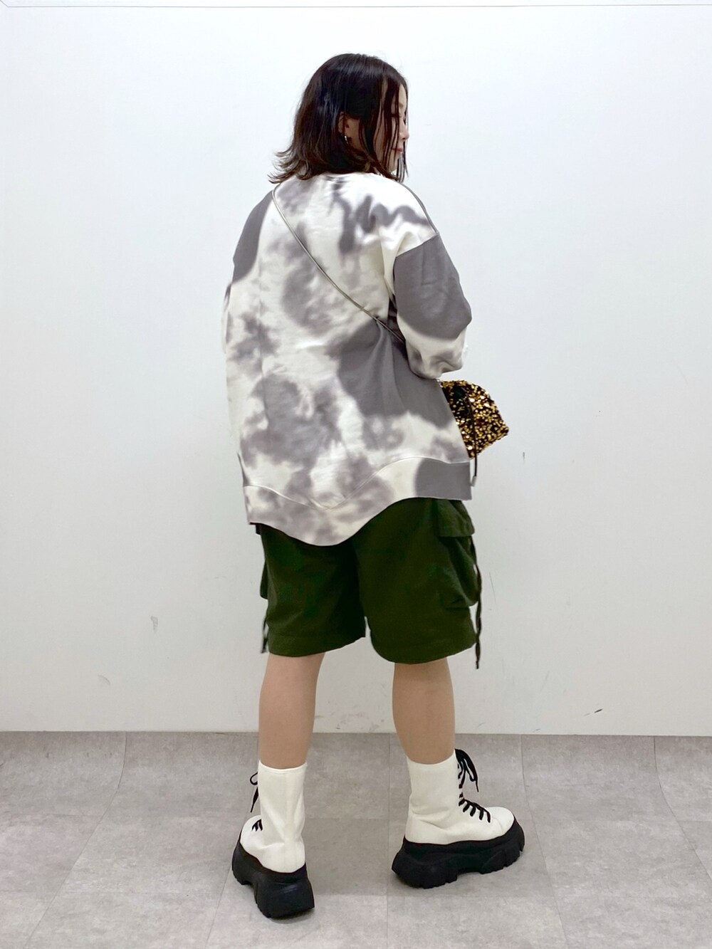 グリーン系のカーゴパンツ、ホワイト系のブーツ、ゴールド系のショルダーバッグを着用したレディースの冬コーディネートの7枚目の写真