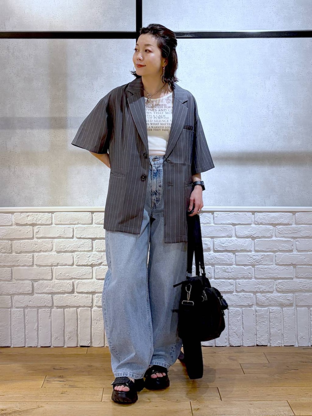 ブラック系のボストンバッグ、ブルー系のデニムパンツ、ブラック系のサンダルを着用したレディースの春コーディネートの9枚目の写真