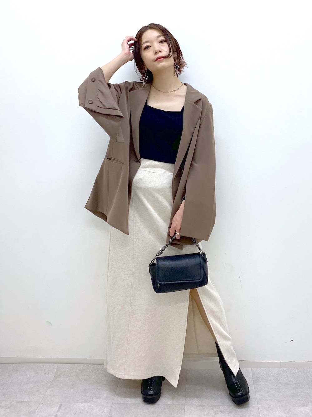 ホワイト系のスカート、ブラック系のブーツ、ブラック系のバッグを着用したレディースの秋コーディネートの2枚目の写真