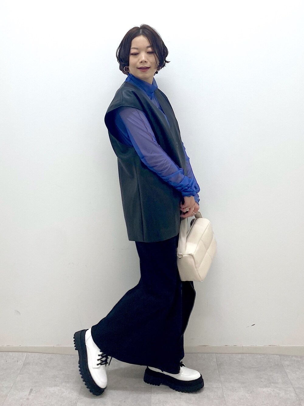 ブラック系のその他アウター、ブラック系のスカート、ホワイト系のショルダーバッグを着用したレディースの秋コーディネートの2枚目の写真