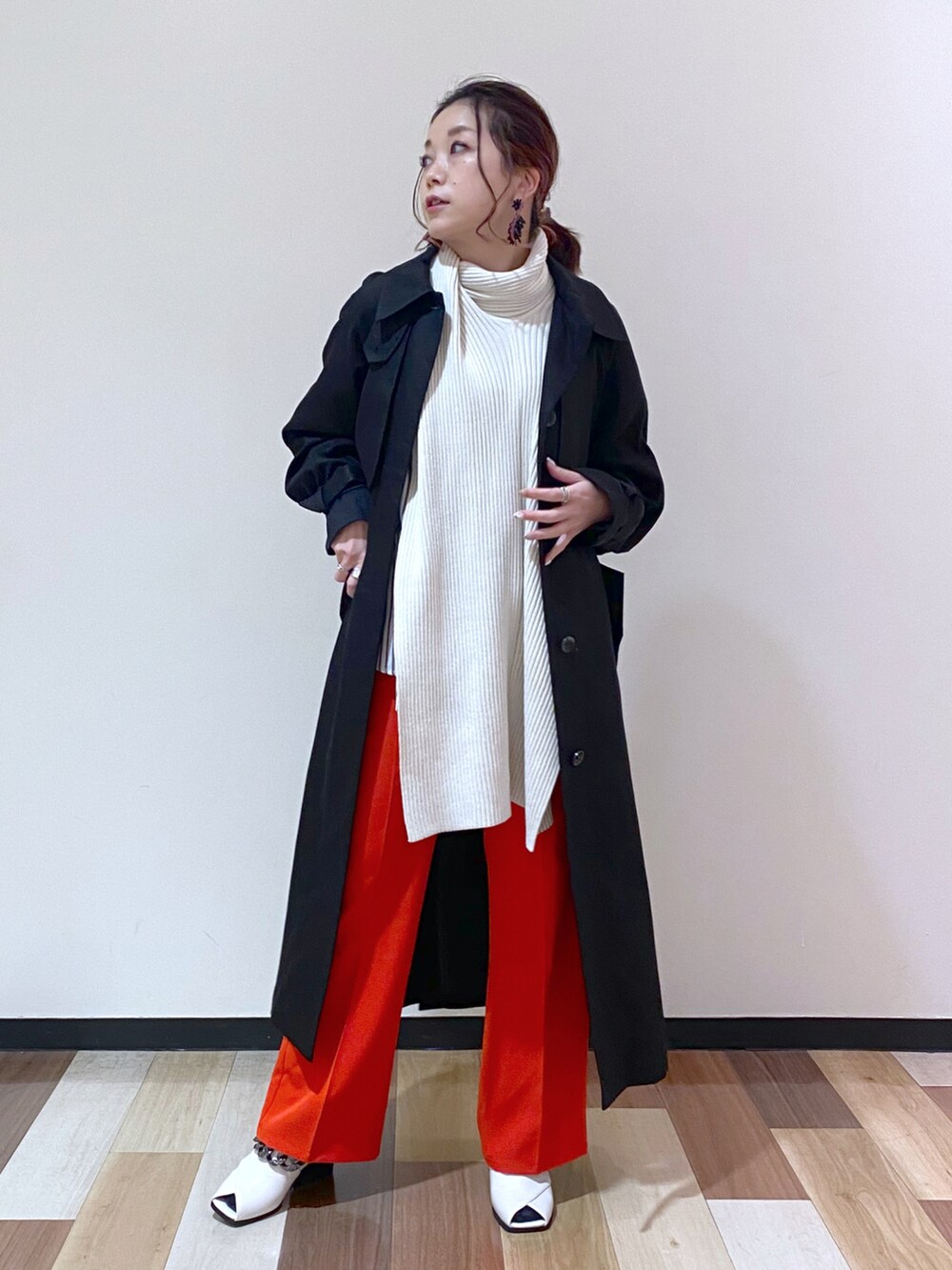 ブラック系のトレンチコート、レッド系のスラックス、ホワイト系のパンプスを着用したレディースの冬コーディネートの2枚目の写真