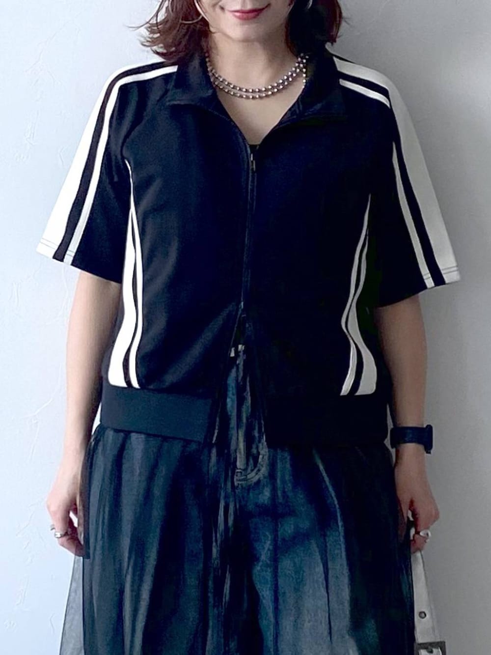 ブラック系のスニーカー、シルバー系のショルダーバッグ、ブルー系のデニムパンツを着用したレディースの夏コーディネートの2枚目の写真