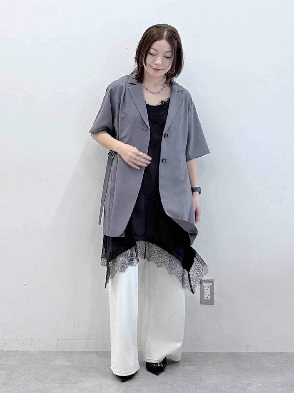 ホワイト系のスラックス、ブラック系のチュニック、ブラック系のサンダルを着用したレディースの春コーディネートの8枚目の写真