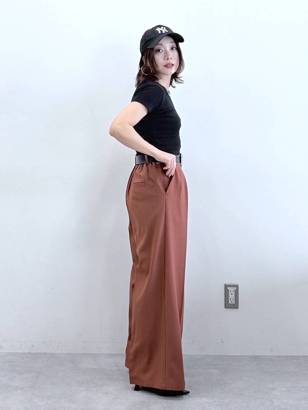 ブラウン系のスラックス、ブラック系のTシャツ/カットソー、ブラック系のキャップを着用したレディースの春コーディネートの4枚目の写真