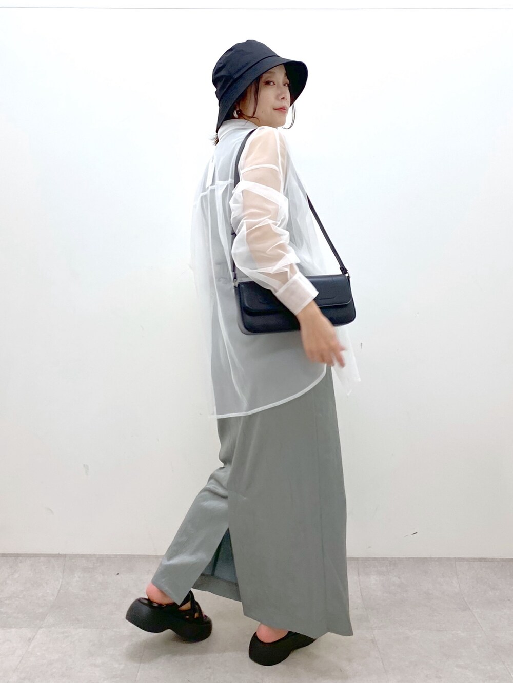 ブルー系のスカート、ブラック系のハンドバッグ、ブラック系のサンダルを着用したレディースの春コーディネートの6枚目の写真