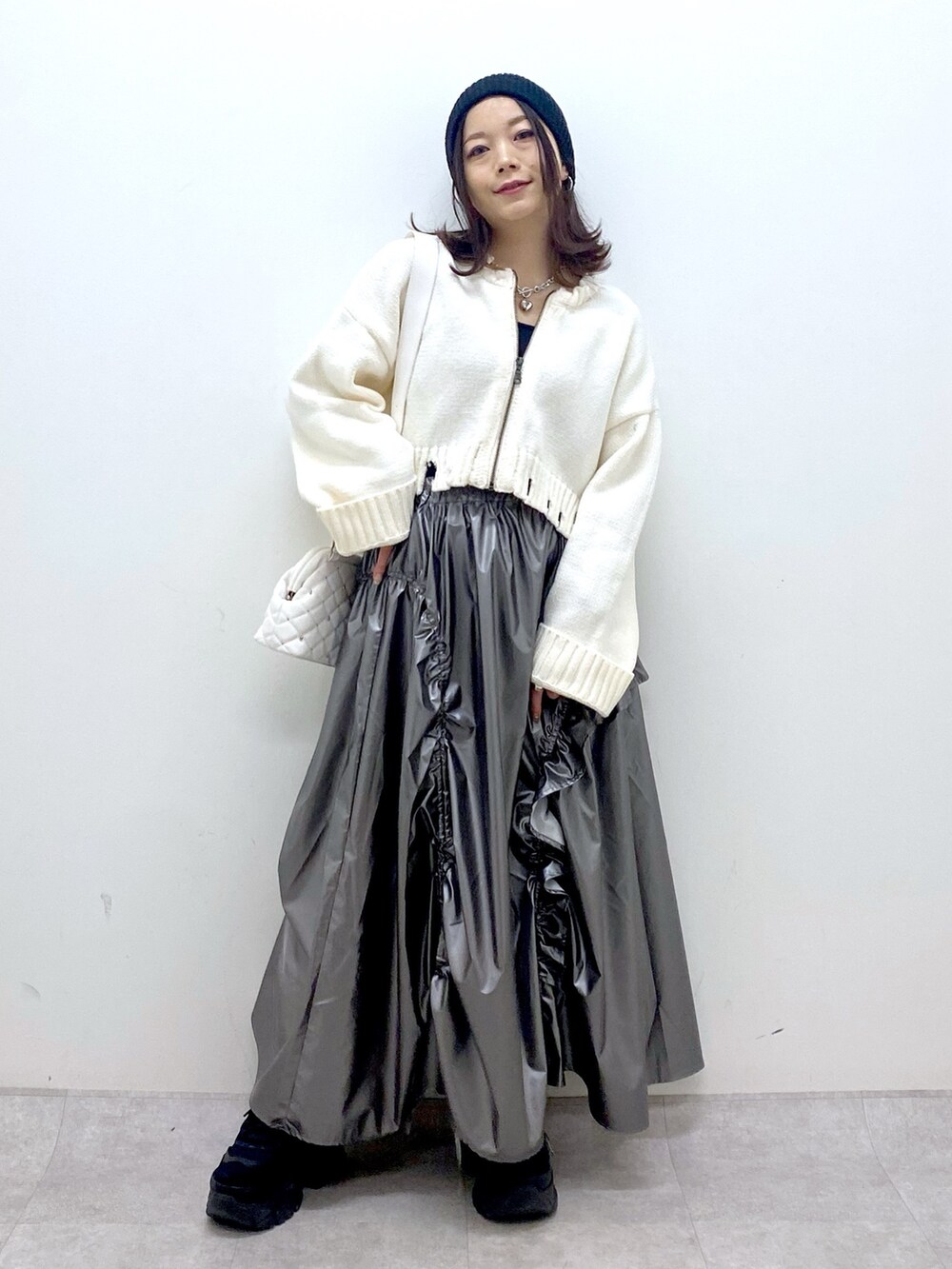 ホワイト系のニット/セーター、シルバー系のスカート、ホワイト系のショルダーバッグを着用したレディースの冬コーディネートの2枚目の写真