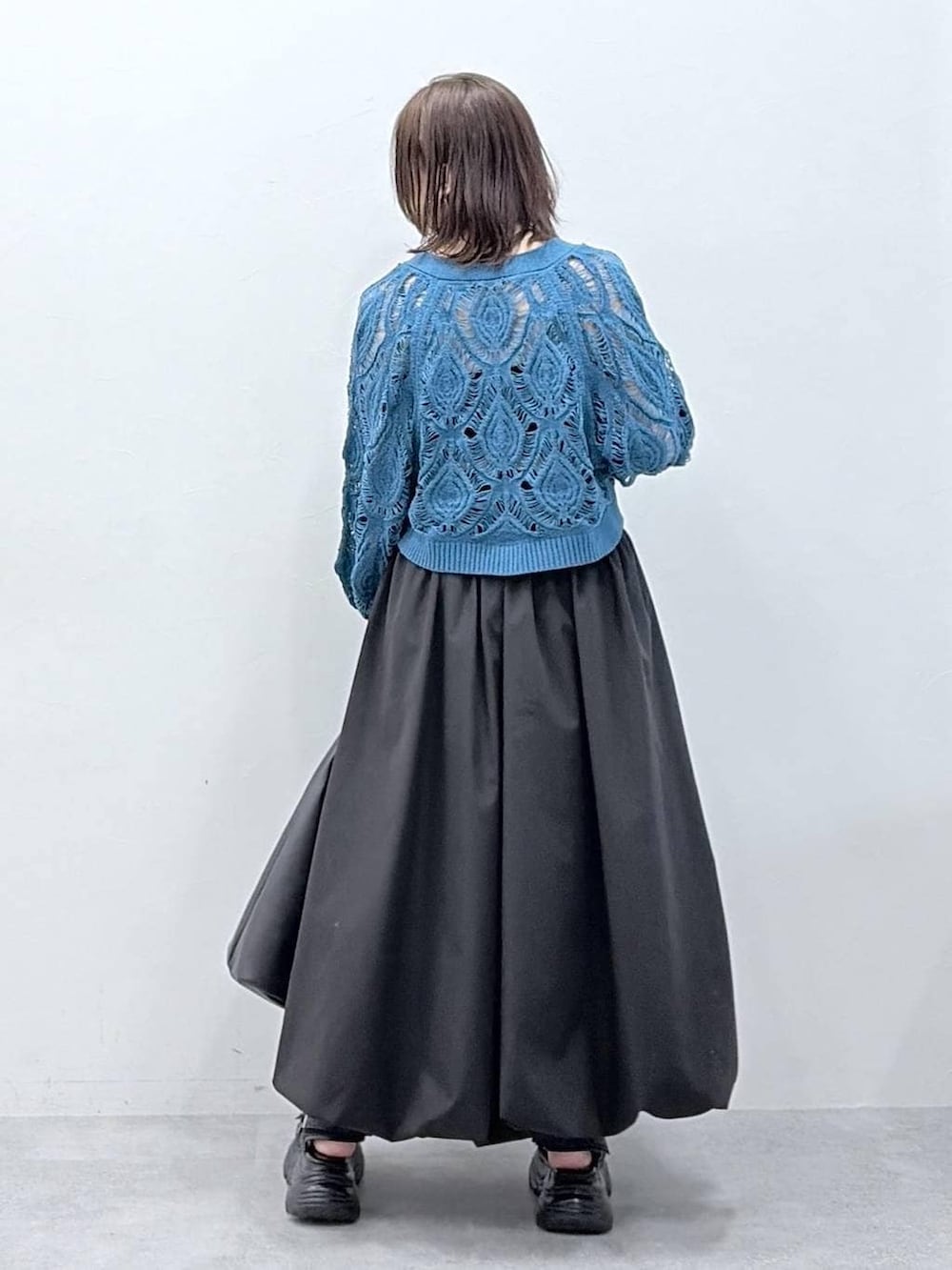 ブルー系のカーディガン/ボレロ、ブラック系のスカートを着用したレディースの春コーディネートの6枚目の写真