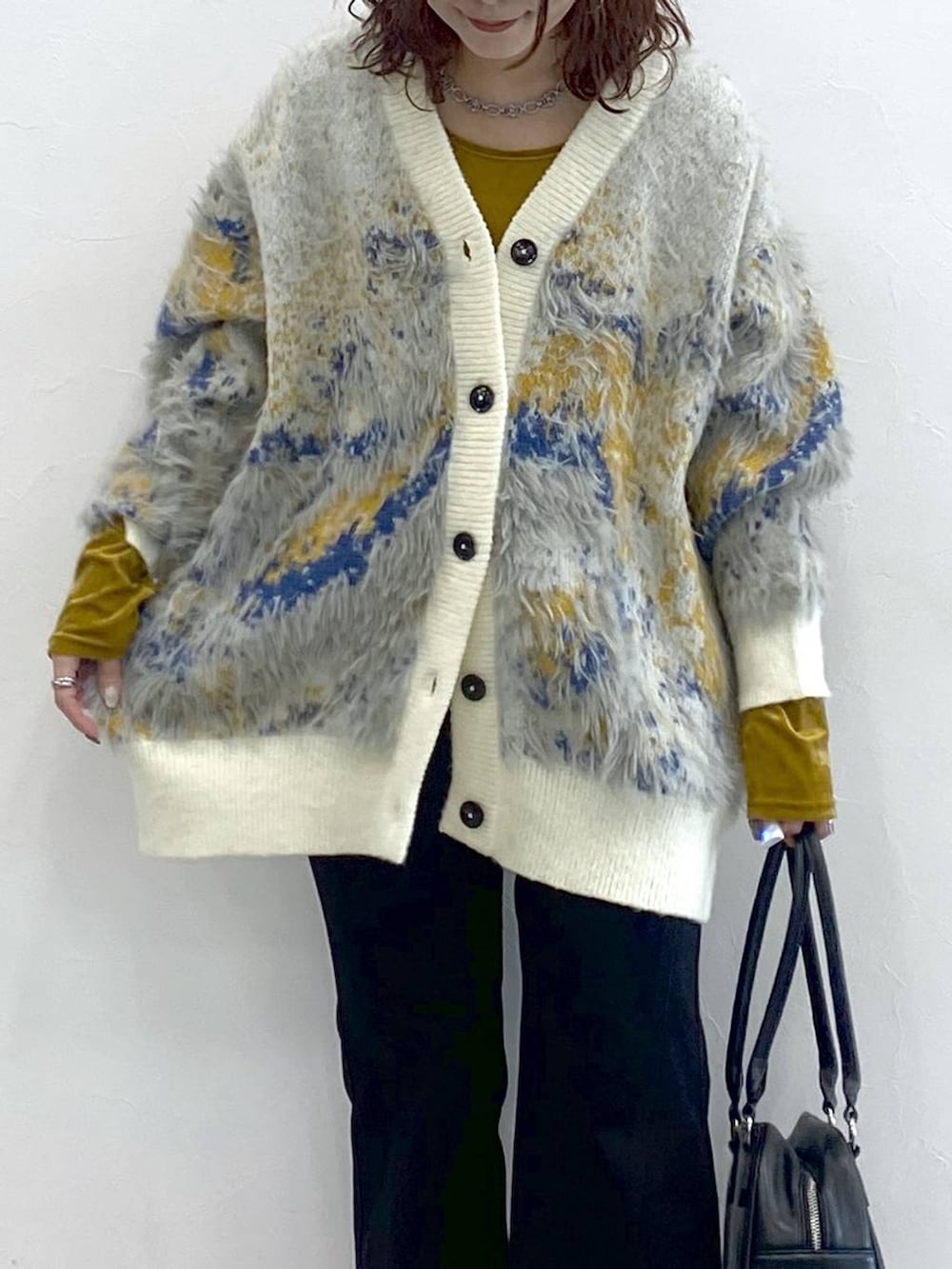 ブラック系のブーツ、ブラック系のボストンバッグ、ホワイト系のカーディガン/ボレロを着用したレディースの秋コーディネートの2枚目の写真