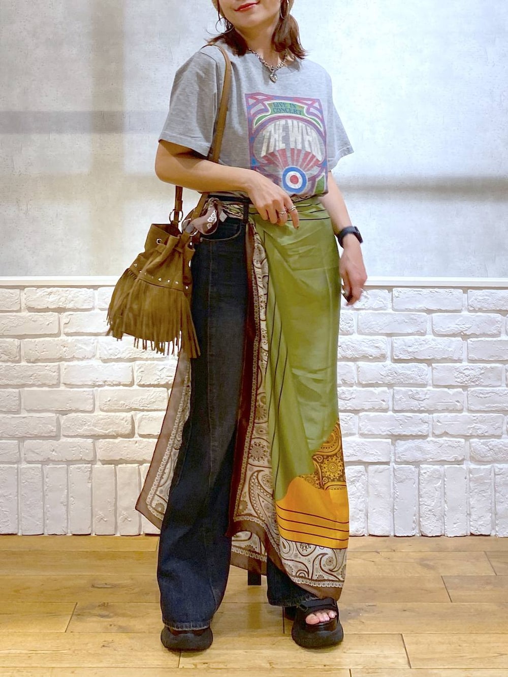 ブラック系のサンダル、ブルー系のデニムパンツ、ベージュ系のショルダーバッグを着用したレディースの夏コーディネートの3枚目の写真