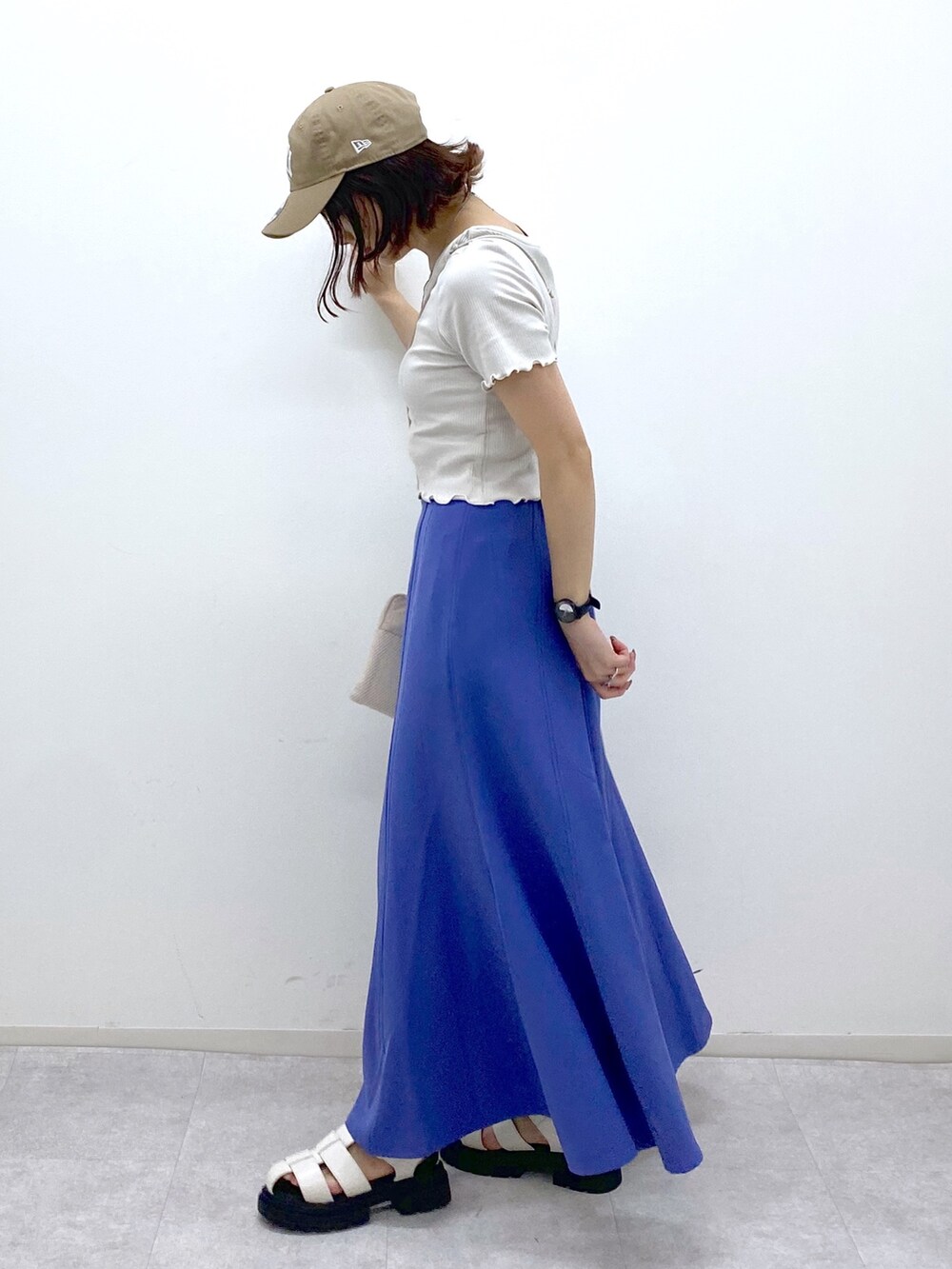 グレー系のトップス、ブルー系のスカート、ベージュ系のショルダーバッグを着用したレディースの夏コーディネートの4枚目の写真