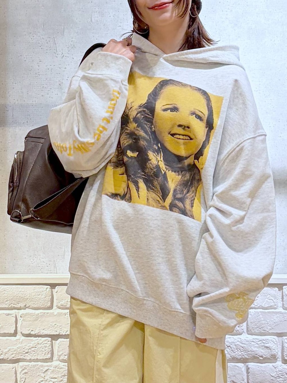 ホワイト系のスニーカー、イエロー系のスウェットパンツ、ブラウン系のショルダーバッグを着用したレディースの春コーディネートの2枚目の写真