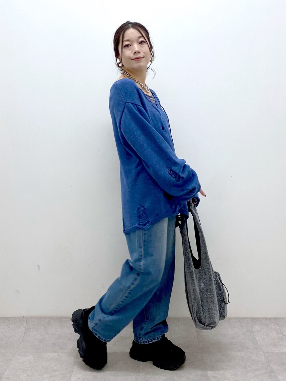 ブルー系のニット/セーター、ブルー系のデニムパンツ、ブラック系のトートバッグを着用したレディースの冬コーディネートの4枚目の写真