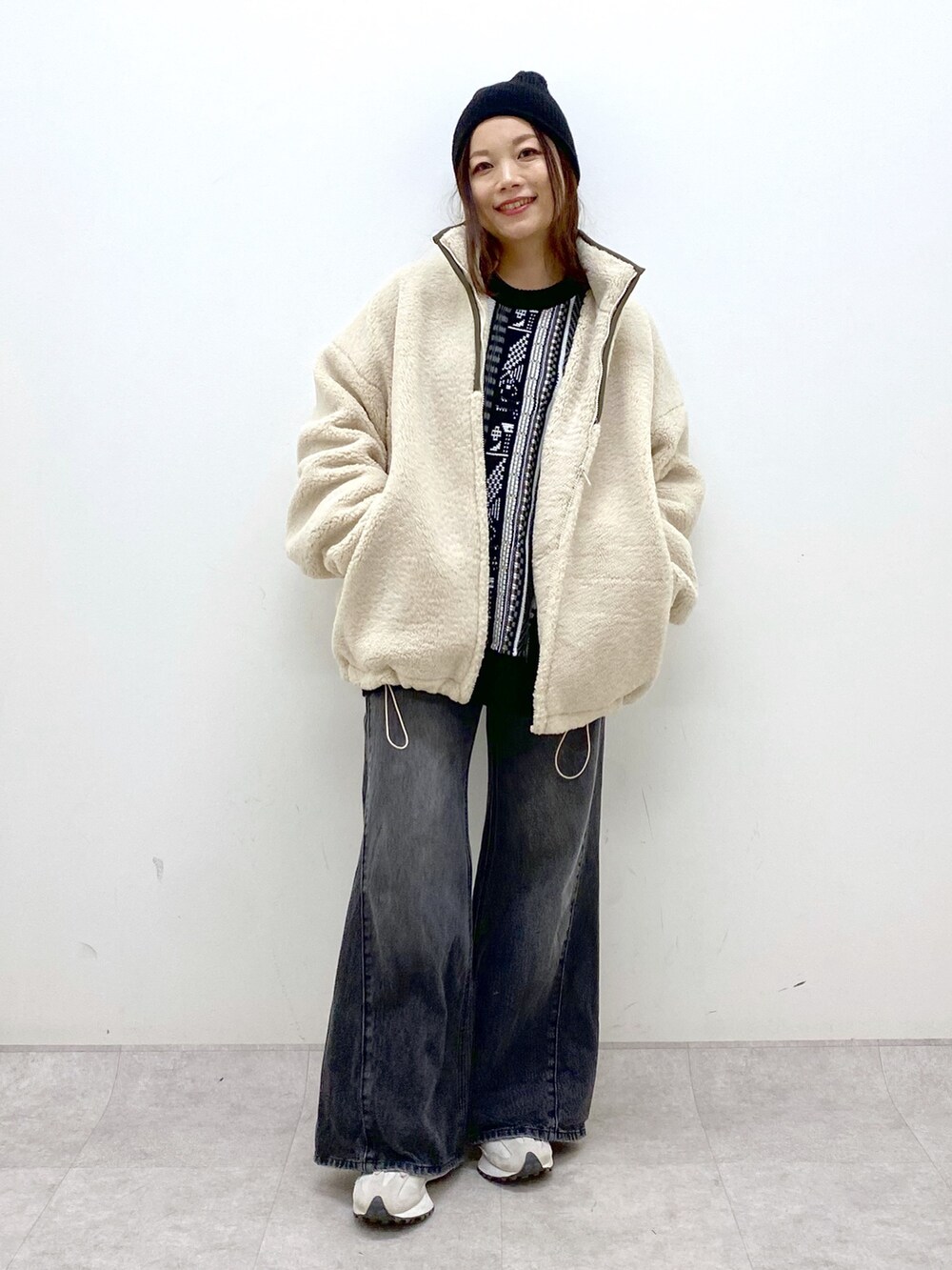 ホワイト系のブルゾン、ブラック系のニット/セーター、ブラック系のデニムパンツを着用したレディースの秋コーディネートの9枚目の写真