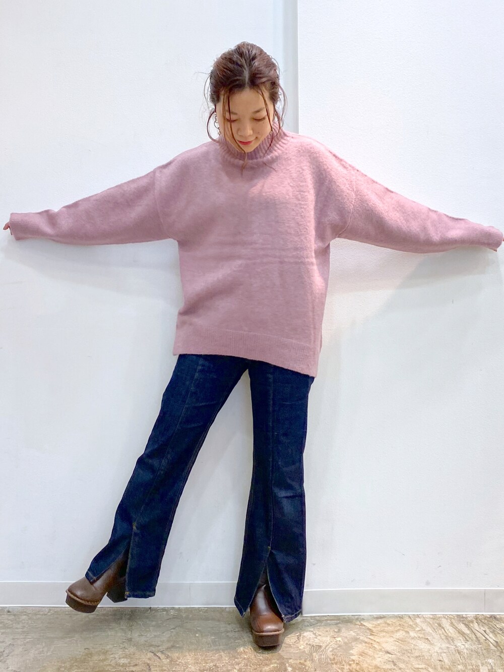 ピンク系のニット/セーター、ブルー系のデニムパンツ、ブラウン系のブーツを着用したレディースの秋コーディネートの2枚目の写真