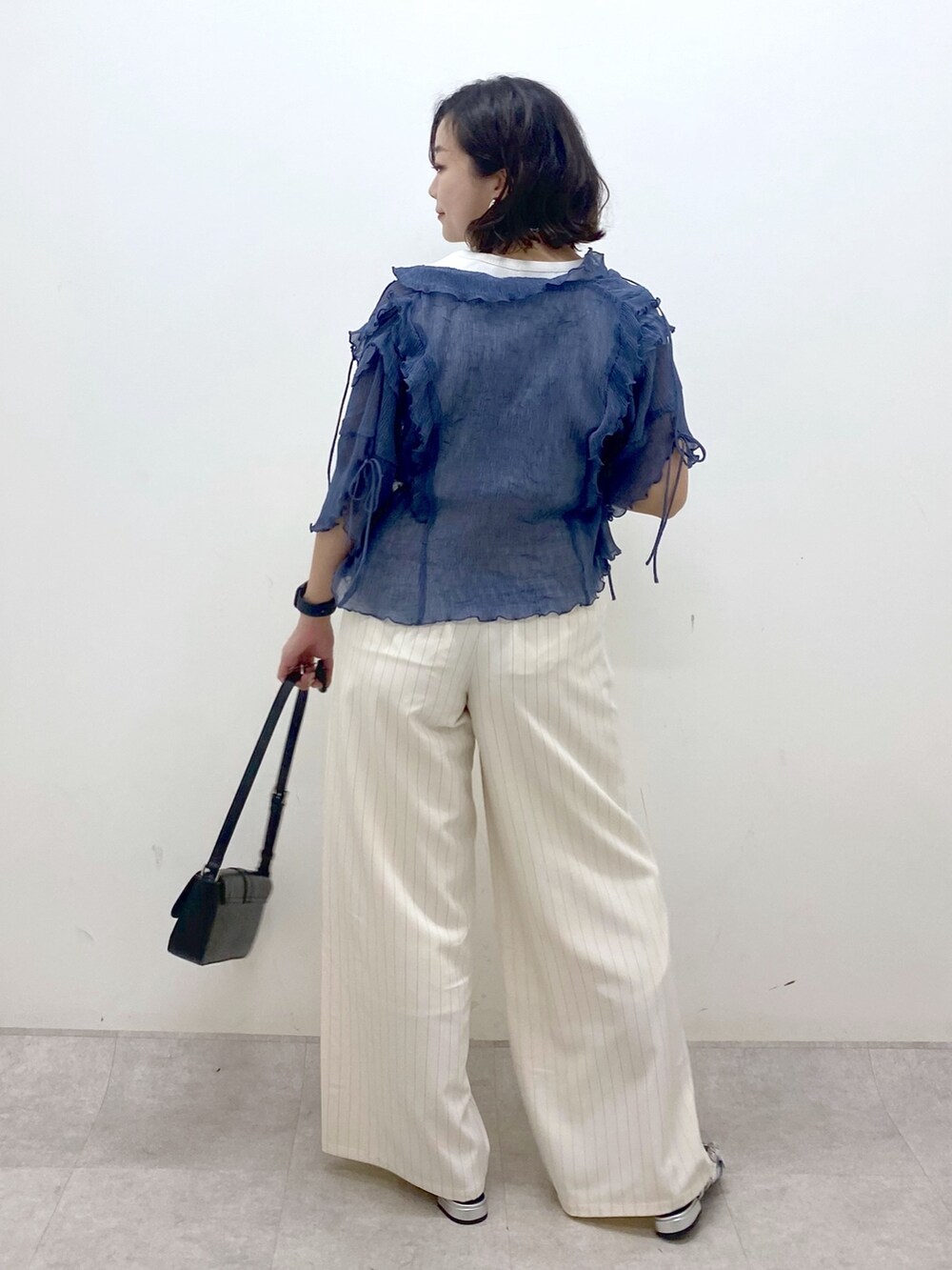 ホワイト系のスラックス、ブラック系のハンドバッグ、シルバー系のパンプスを着用したレディースの夏コーディネートの6枚目の写真