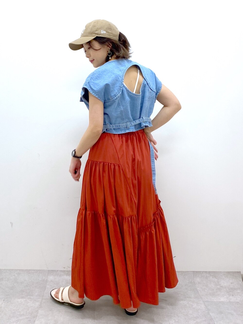 オレンジ系のスカート、ブルー系のその他アウター、ブラック系のキャミソールを着用したレディースの夏コーディネートの2枚目の写真