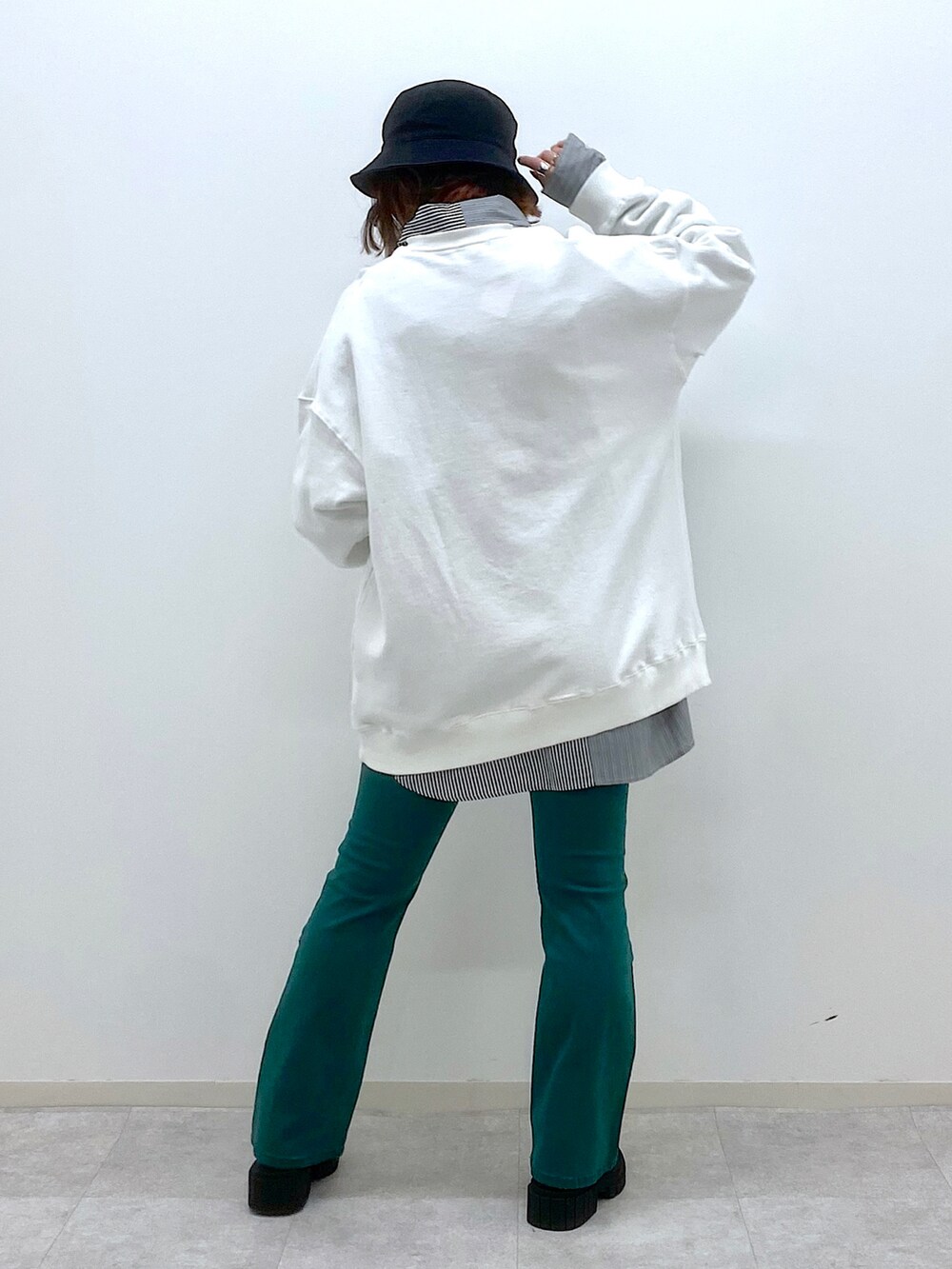 グリーン系のデニムパンツ、ブラック系のローファー、ホワイト系のスウェットを着用したレディースの冬コーディネートの3枚目の写真