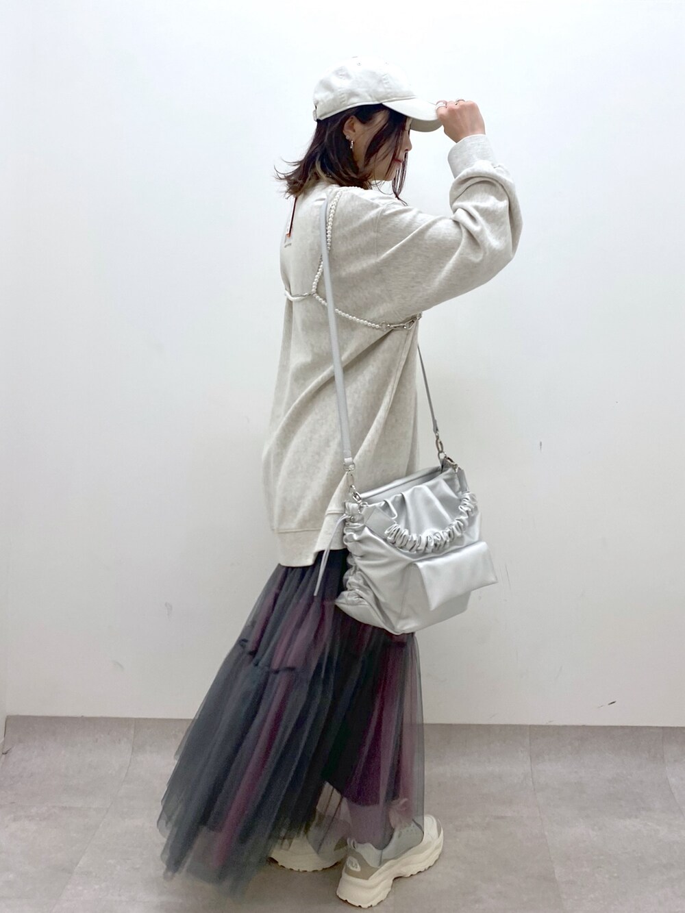 ベージュ系のスウェット、シルバー系のショルダーバッグ、グレー系のスカートを着用したレディースの春コーディネートの6枚目の写真
