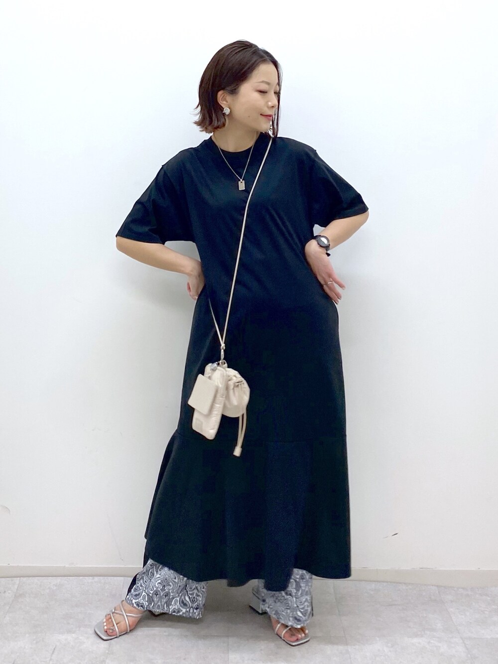 ブラック系のワンピース、ベージュ系のショルダーバッグ、シルバー系のサンダルを着用したレディースの夏コーディネートの5枚目の写真