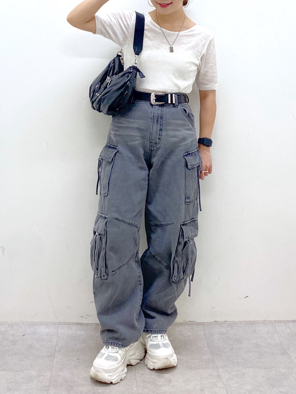 ブラック系のデニムパンツ、ホワイト系のスニーカー、ブラック系のショルダーバッグを着用したレディースの夏コーディネートの3枚目の写真