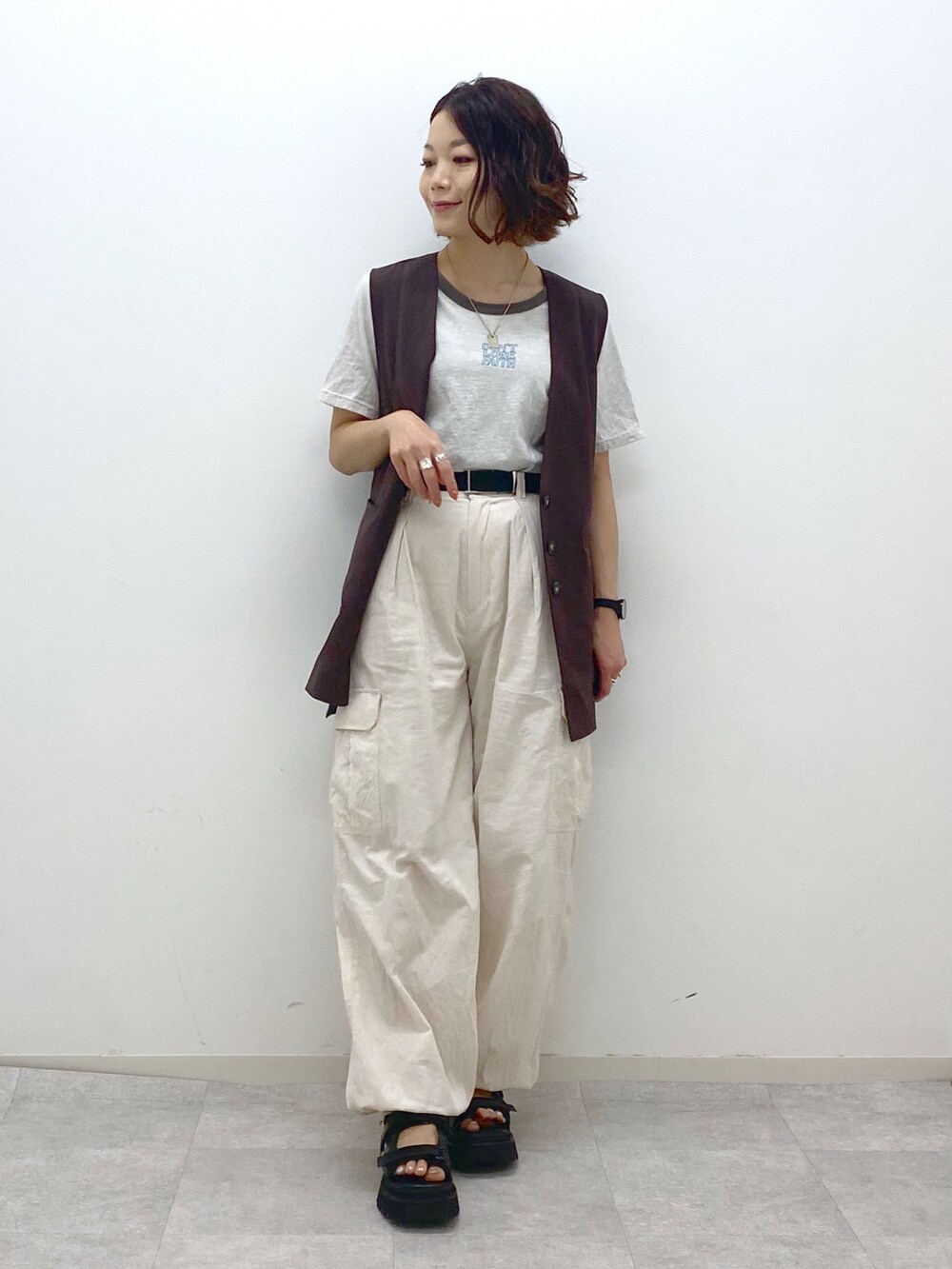ホワイト系のカーゴパンツ、ブラック系のサンダル、ベージュ系のTシャツ/カットソーを着用したレディースの夏コーディネートの5枚目の写真
