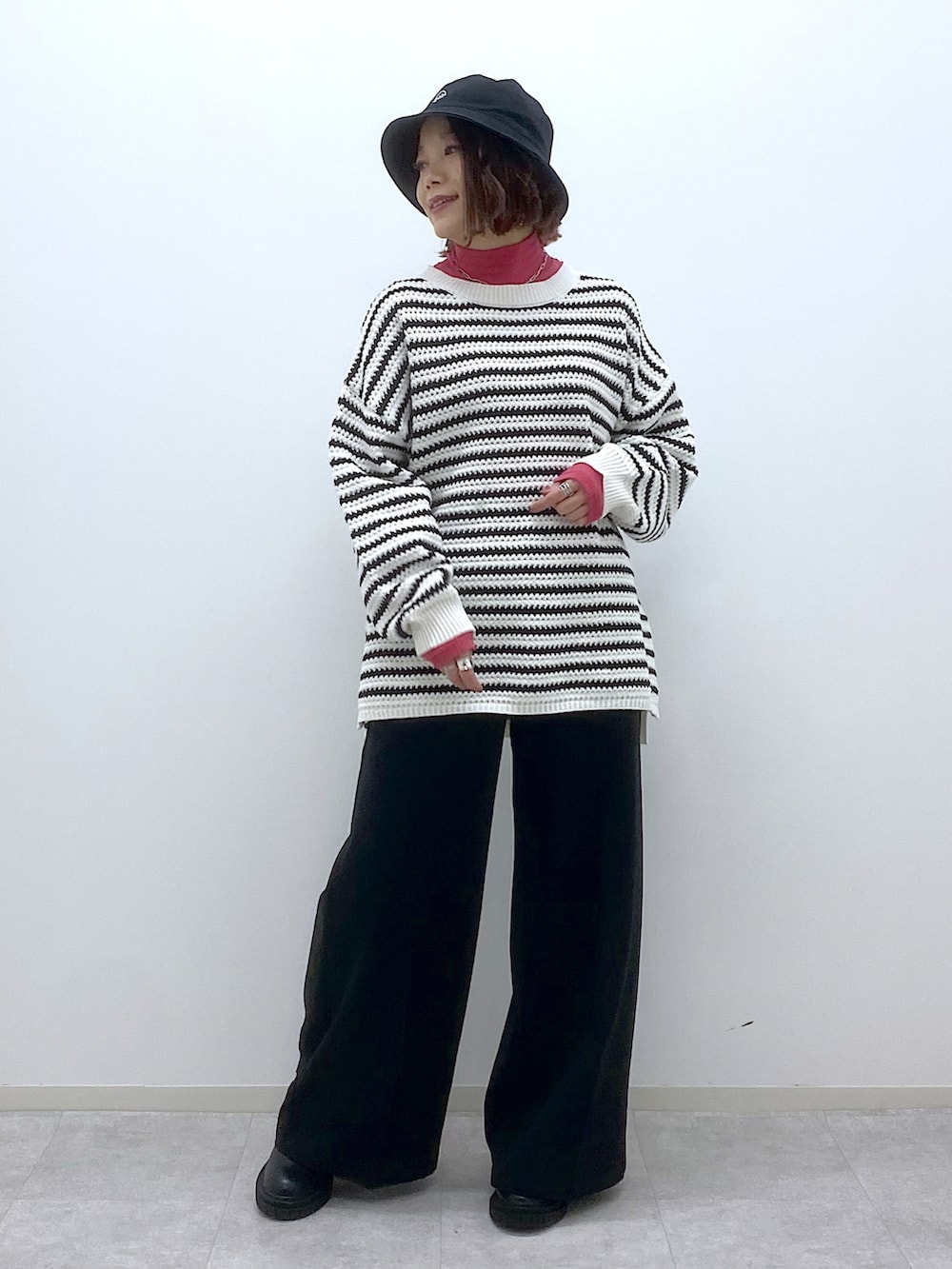 ホワイト系のニット/セーター、ピンク系のTシャツ/カットソー、ブラック系のスラックスを着用したレディースの春コーディネートの2枚目の写真