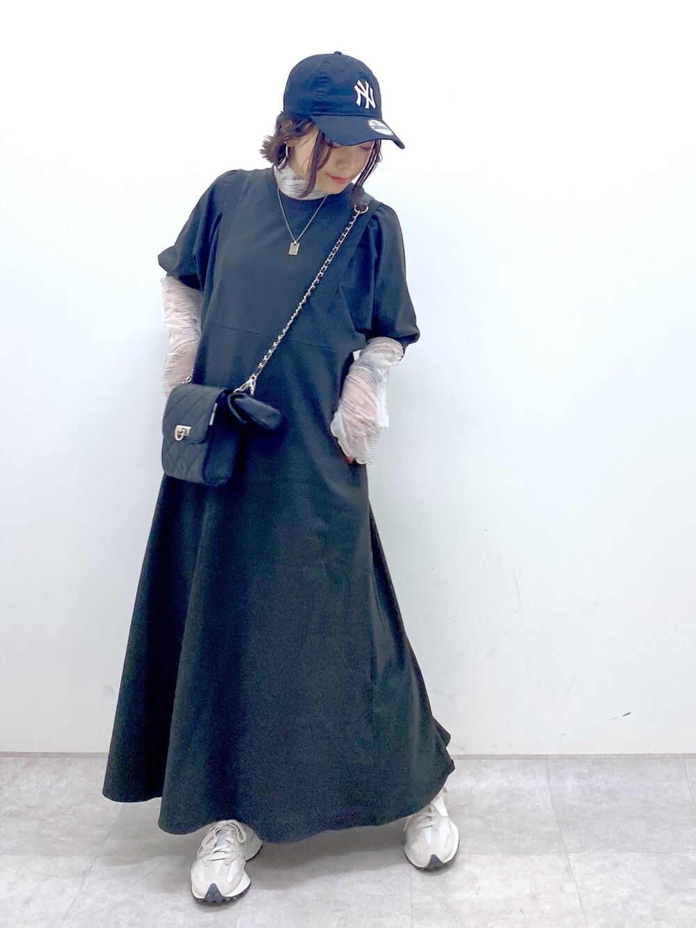 ブラック系のワンピース、ベージュ系のスニーカー、ブラック系のバッグを着用したレディースの春コーディネートの5枚目の写真