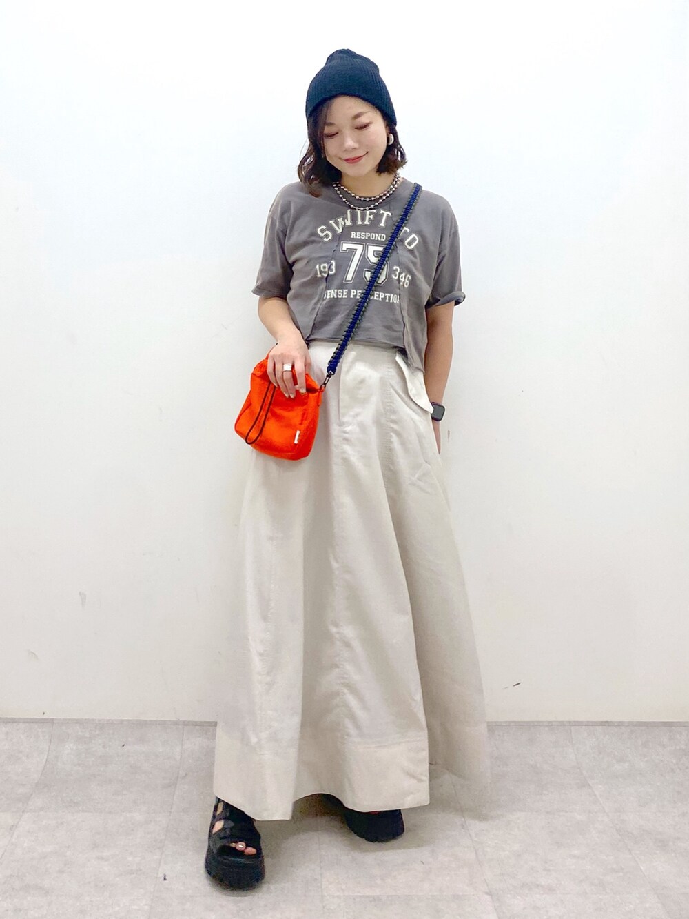 ブラック系のTシャツ/カットソー、オレンジ系のショルダーバッグ、ベージュ系のスカートを着用したレディースの夏コーディネートの9枚目の写真