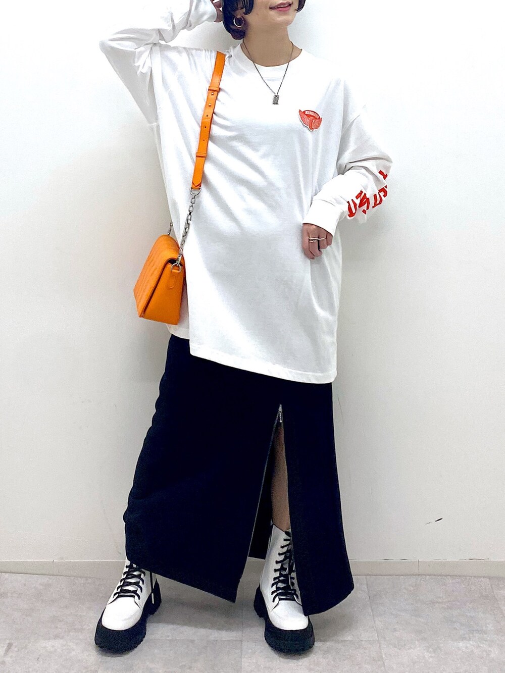 ブラック系のスカート、ホワイト系のブーツ、オレンジ系のショルダーバッグを着用したレディースの秋コーディネートの5枚目の写真