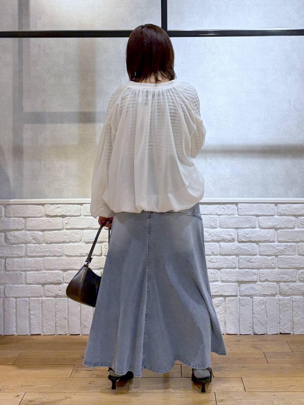 ブラウン系のハンドバッグ、ホワイト系のニット/セーター、ブラック系のサンダルを着用したレディースの春コーディネートの6枚目の写真