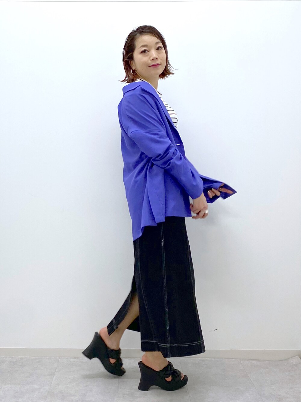 ブラック系のデニムスカート、ブラック系のサンダル、パープル系のテーラードジャケットを着用したレディースの春コーディネートの2枚目の写真
