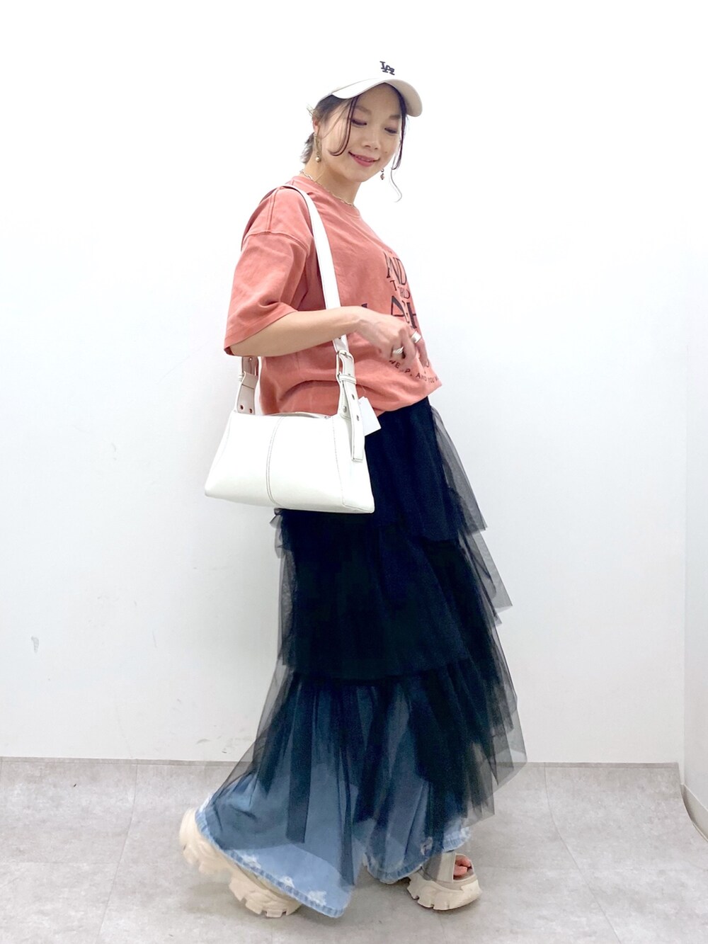 ブルー系のデニムパンツ、オレンジ系のTシャツ/カットソー、ブラック系のスカートを着用したレディースの夏コーディネートの2枚目の写真