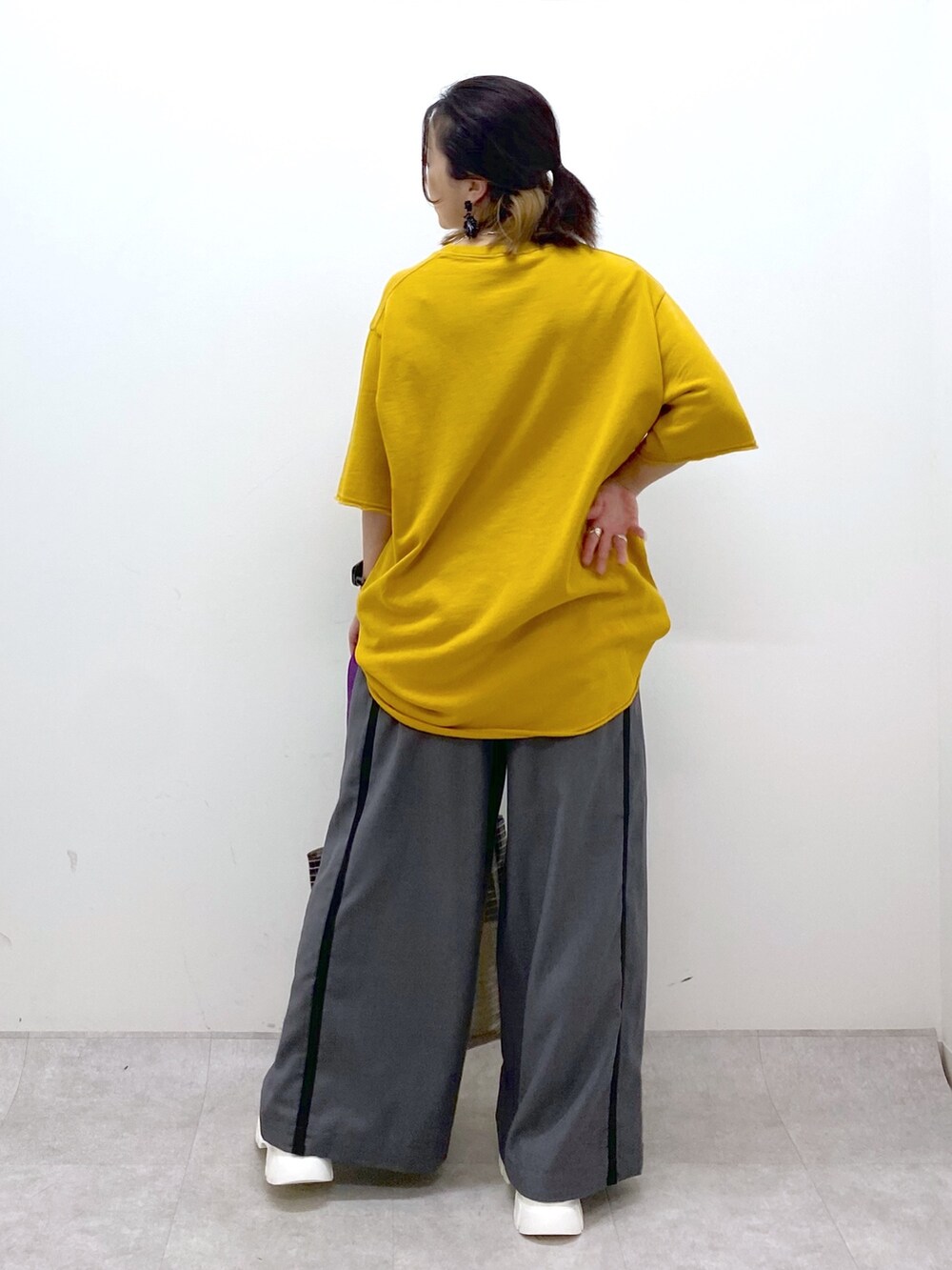 イエロー系のTシャツ/カットソー、グレー系のスラックス、グレー系のトートバッグを着用したレディースの夏コーディネートの5枚目の写真