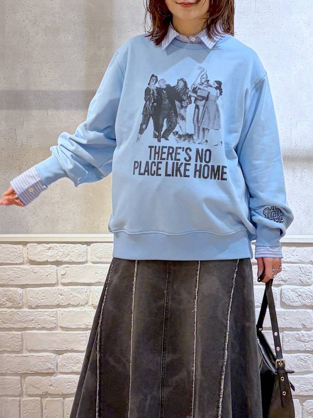 ブラック系のスニーカー、ブラック系のハンドバッグ、ブラック系のデニムスカートを着用したレディースの春コーディネートの2枚目の写真