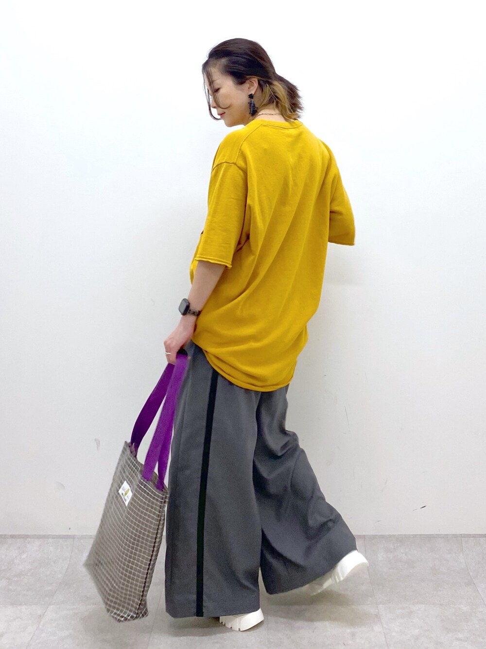 イエロー系のTシャツ/カットソー、グレー系のスラックス、グレー系のトートバッグを着用したレディースの夏コーディネートの4枚目の写真